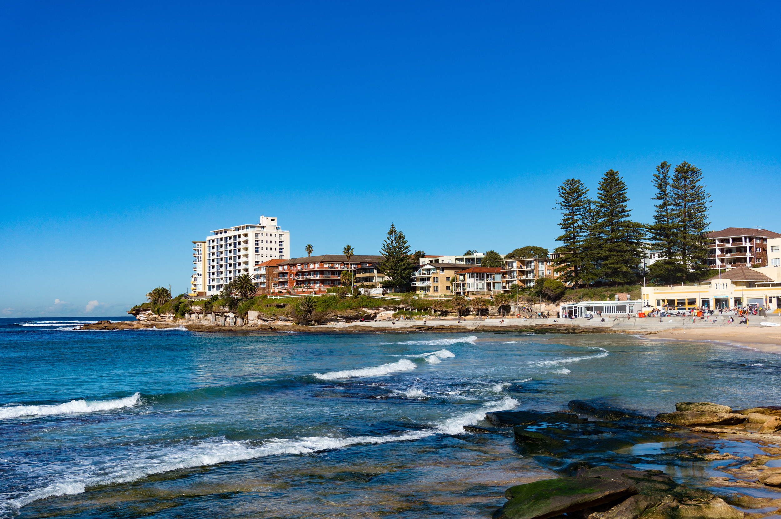 Sunny day on Cronulla beach, Australia. Urban beach with sand and rock shore with water view property on the background. Cronulla, NSW, Australia